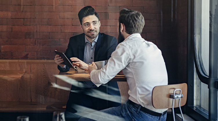 Two men chatting with an ipad while drinking coffee