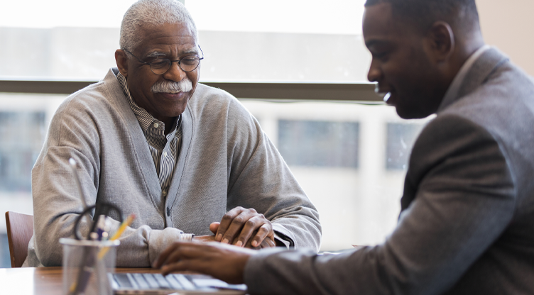 older man in meeting with younger man on laptop