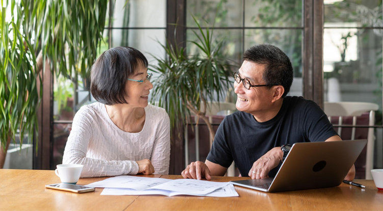 retired asian couple at a desk looking at documents