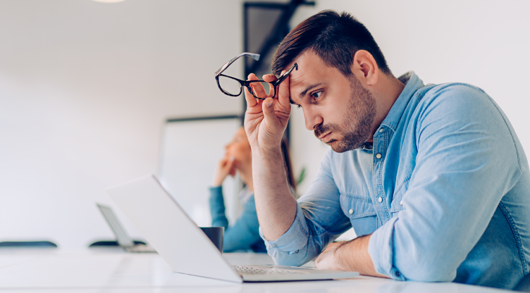stressed man looking at laptop screen