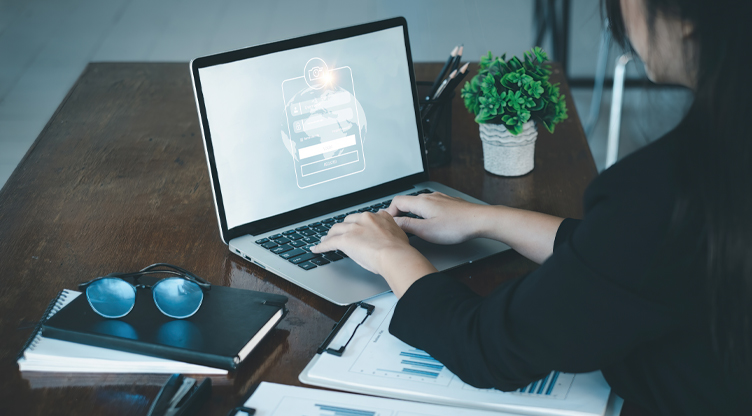 woman sitting down at a desk signing into her laptop