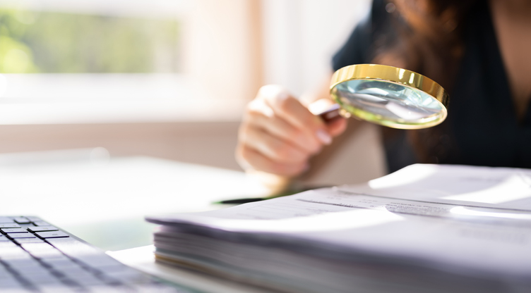 woman using magnifying glass to review documents