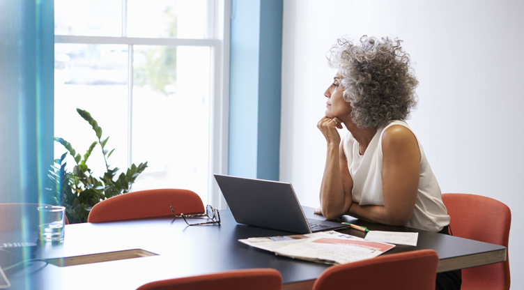 women contemplating soultions at her desk looking out the window